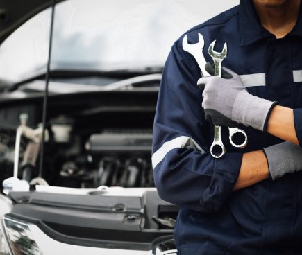 Car mechanic in front of car holding two wrenches