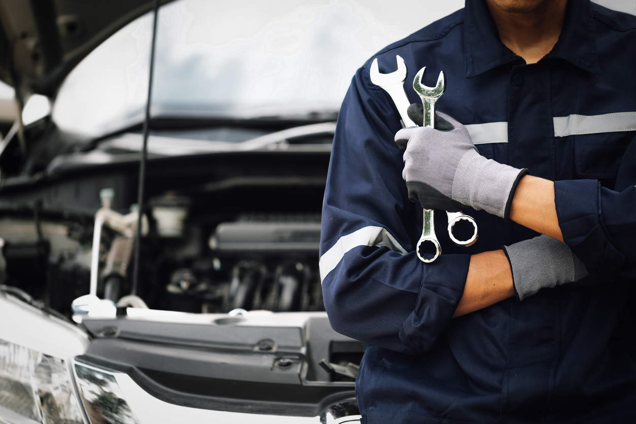 Car mechanic in front of car holding two wrenches