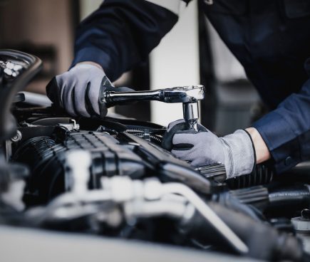 Mechanic working on car engine in garage