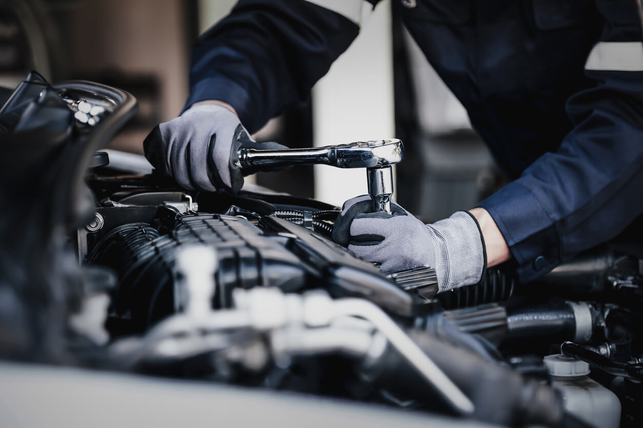 Mechanic working on car engine in garage