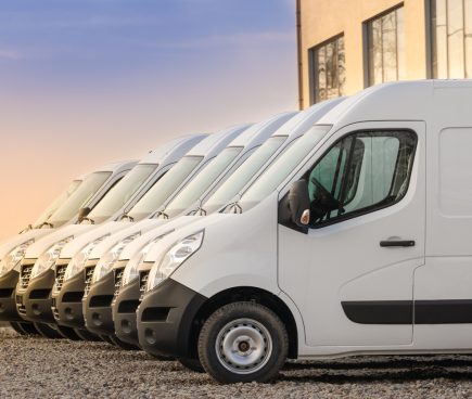 White commercial vans lined up in a row in parking lot