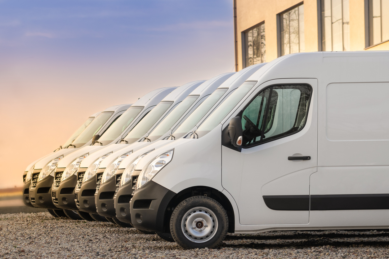 White commercial vans lined up in a row in parking lot